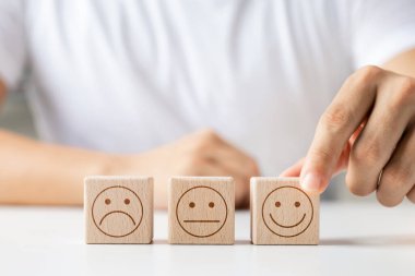 Müşteri memnuniyeti anketi konsepti, müşteri eli gülen yüzlü ahşap küpü seçer, memnuniyet için en iyi hizmet derecesi.