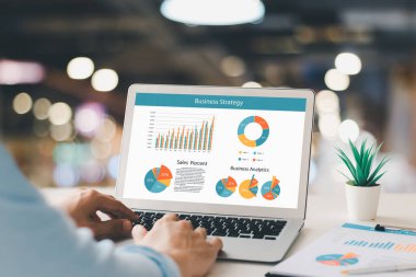 Muhasebe konsepti. İş adamı finans satış verilerini ve ekonomik büyüme grafiğini analiz eden bir dizüstü bilgisayar kullanarak çalışıyor.