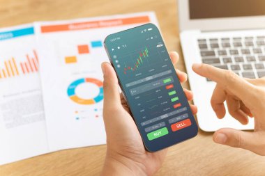 İşadamları borsa yatırımlarıyla ticaret verilerini analiz etmek için akıllı telefonları kullanıyorlar. Ekranda borsa grafiği olan akıllı telefon. Finansal borsa.