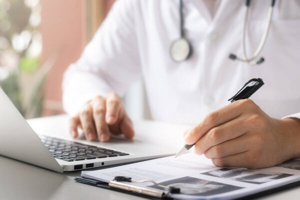 врач анализирует медицинское заключение Тщательное физическое обследование с помощью рентгеновского снимка, записи данных пациентов с помощью ноутбука.