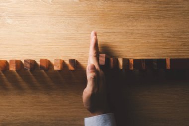 Risk yönetimi ve iş stratejisi konsepti, iş adamlarının elleri dominoların sürekli düşmesini engelliyor ve gelecekteki krizin risklerini engelliyor.
