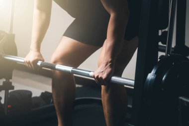 Halterle egzersiz yapan, ağırlık antrenmanı yapan sabah güneşinde spor salonunda vücut gücü toplayan bir adam..