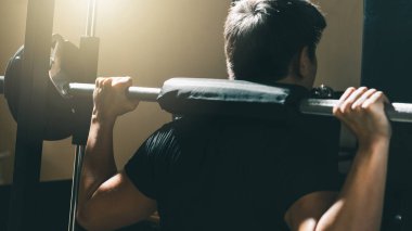 Halterle egzersiz yapan, ağırlık antrenmanı yapan sabah güneşinde spor salonunda vücut gücü toplayan bir adam..