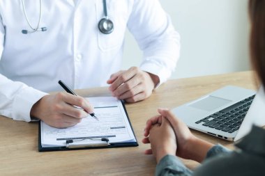 Doktor hastayla konuşur, tedavi raporlarını analiz eder, röntgen ile detaylı bir fiziksel muayene yapar, hasta verilerini dizüstü bilgisayarla kaydeder..