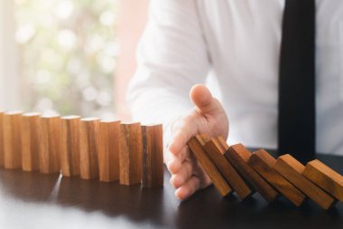 Risk yönetimi, iş adamı eli... Tahta dominoların sürekli düşmesini durdurun, iş krizinin etkisini durdurun. başarı için iş problemlerini çözmek.