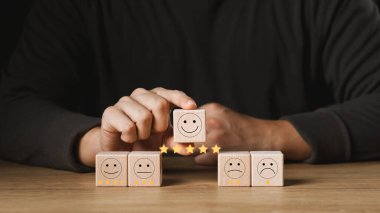 Müşteri memnuniyeti anketi konsepti, müşteri eli gülen yüzlü ahşap küpü seçer, memnuniyet için en iyi hizmet derecesi.