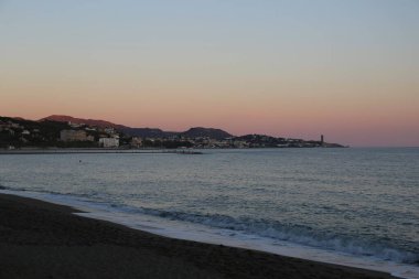 Deniz manzaralı ve deniz kenarında pembe günbatımı olan bir yaz akşamı