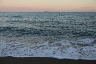 Deniz manzaralı ve deniz kenarında pembe günbatımı olan bir yaz akşamı