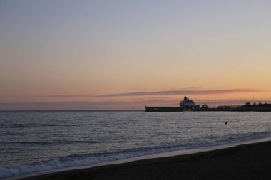 Deniz manzaralı ve deniz kenarında pembe günbatımı olan bir yaz akşamı