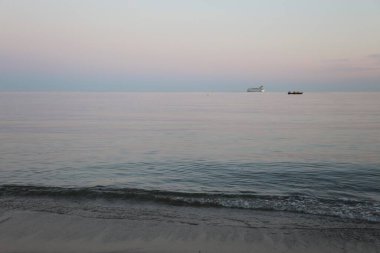 Deniz manzaralı ve deniz kenarında pembe günbatımı olan bir yaz akşamı