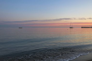 Deniz manzaralı ve deniz kenarında pembe günbatımı olan bir yaz akşamı