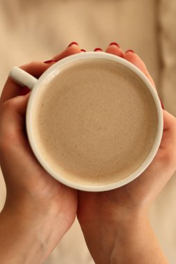  Bir evde elinde bir fincan sütlü kahve tutan kişi.