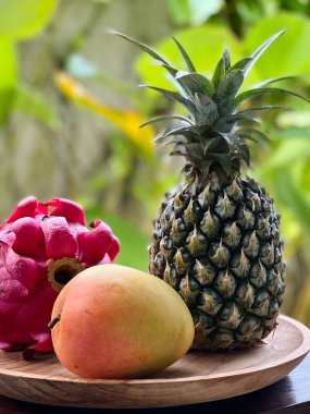 ejderha meyvesi, ananas ve mango tropikal olarak ahşap tabakta