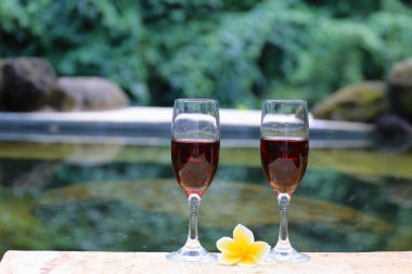 Tropiklerde yüzme havuzunun yanında kırmızı şarap bardakları