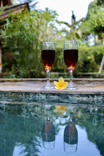 glasses with red wine near the swimming pool in the tropics