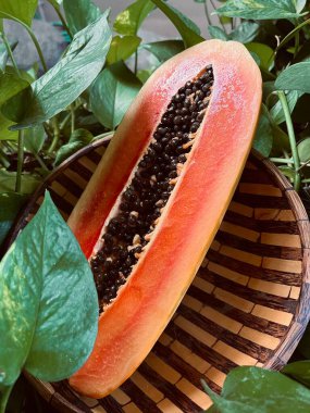 Tahta tabakta papaya meyvesi ve yeşil yapraklar.