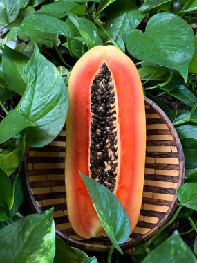 Tahta tabakta papaya meyvesi ve yeşil yapraklar.