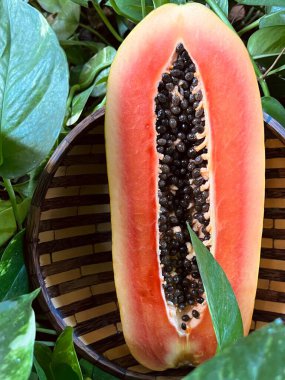 Tahta tabakta papaya meyvesi ve yeşil yapraklar.