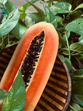 Tahta tabakta papaya meyvesi ve yeşil yapraklar.