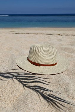 Hasır şapka ve kumdaki palmiye ağacının gölgesi.