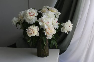  Masadaki vazoda bir buket beyaz çiçek şakayığı var.