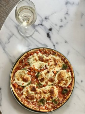 Pizza ve beyaz şarap masada.