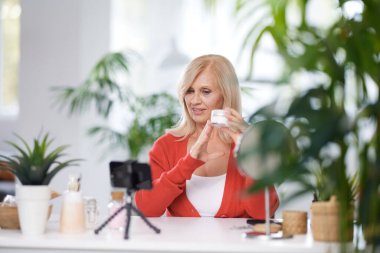 Yaşlı bir vlogger evde oturuyor ve yeni anti-yaş kreminden bahsediyor..