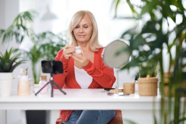 Yaşlı bir vlogger evde oturuyor ve yeni anti-yaş kreminden bahsediyor..