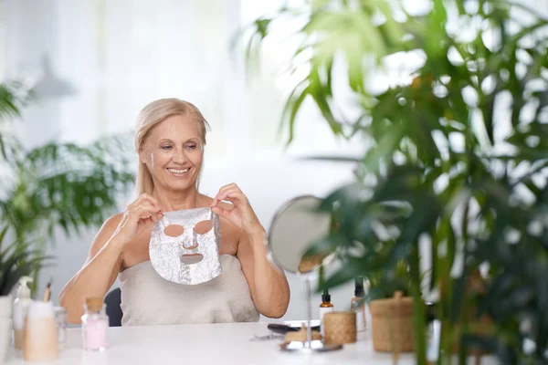 Senior Woman Putting Beauty Face Mask Her Face While Sitting — Stock Photo, Image