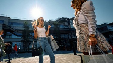 İki çekici genç kadın ellerinde alışveriş torbalarıyla sokakta durmuş sohbet ediyorlar..