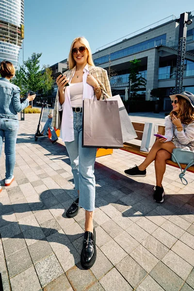 一个快乐的女人站在街上 手里拿着购物袋 一边购物一边打电话 黑色星期五 — 图库照片