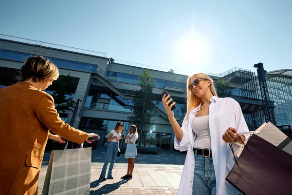 Atrakcyjna Blondynka Stoi Ulicy Torbami Zakupy Telefonem Sprawdza Swoje Konto — Zdjęcie stockowe