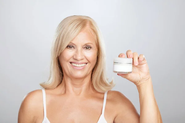 Happy Senior Blond Woman Holding Age Creme Hand Looking Camera — Stock Photo, Image