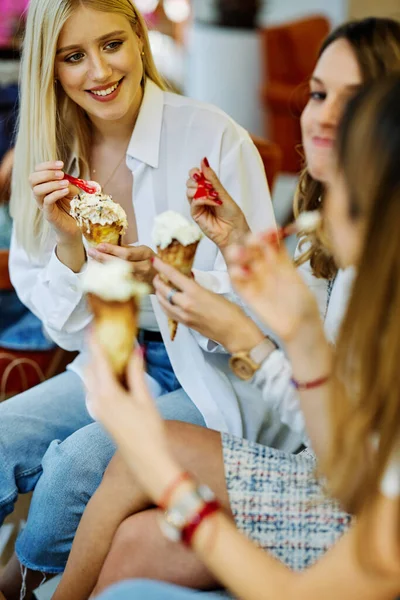 Üç mutlu kız bir restoranda oturmuş alışveriş yaptıktan sonra sohbet ediyor ve dondurma yiyorlar..