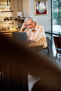Bir son sınıf öğrencisi kafeteryada oturuyor ve internetteki derslerini dikkatle izliyor..