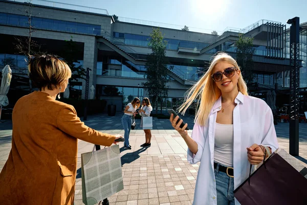 Atrakcyjna Blondynka Stoi Ulicy Torbami Zakupy Telefonem Sprawdza Swoje Konto — Zdjęcie stockowe