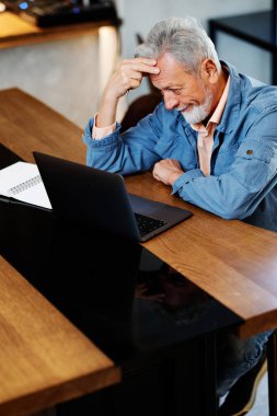 Bir son sınıf öğrencisi kafeteryada oturuyor ve bilgisayarındaki dersleri takip ediyor..