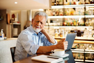 Bir son sınıf öğrencisi evde oturuyor ve boynunu okşuyor. Oturup ders çalışmaktan yoruldu..