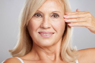 Güzel, yaşlı bir bayanın buruşuk tenine dokunuşunun yakın çekimi. Güzellik fotoğrafçılığı