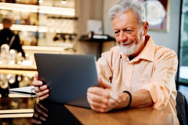 Bir son sınıf öğrencisi kafeteryada oturuyor ve internetteki derslerini dikkatle izliyor..