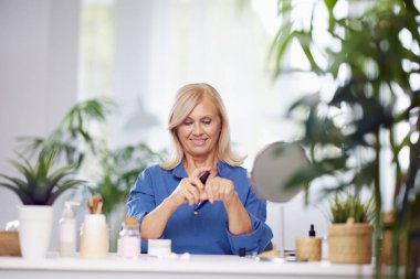Son sınıf öğrencisi bir kadın evde oturuyor ve eline fondöten kremi sürüyor. Yeni bir ürün deniyor.