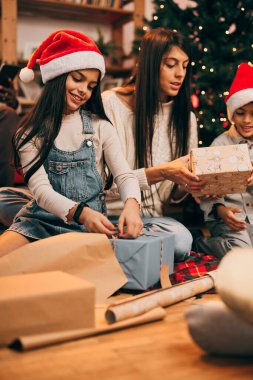 Mutlu, çok kültürlü bir aile Noel ağacının önünde oturuyor ve hediyelerini evlerinde paylaşıyorlar..
