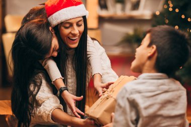 Mutlu bir anne çocuklarıyla evde oturuyor ve onlardan bir Noel hediyesi alıyor..
