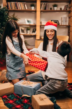 Çocuklar hediyeler için kavga ederken anneleri oturur ve tartışmaları Noel ruhuyla çözmeye çalışır..