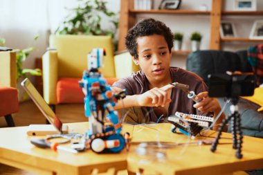 Zeki bir Afro-Amerikalı çocuk kendini bir video bloğu için kaydediyor ve nasıl robot yapılacağını gösteriyor. Robot bilimi ve yapay zeka eğitimi.