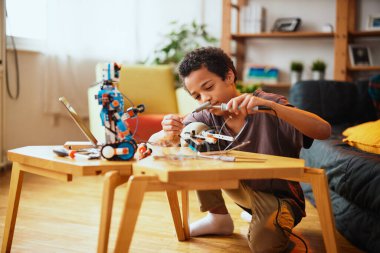 Evde robot yapan Afro-Amerikalı bir çocuk. Evde robotik eğitimi.