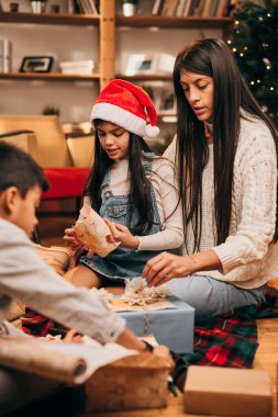 Mutlu bir aile yerde birlikte oturur ve Noel arifesinde Noel hediyelerini paketler. Noel ve Yeni Yıl
