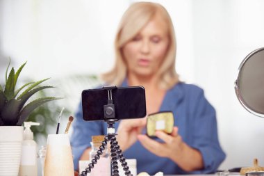 Evde oturup yeni güzellik ürünleri hakkında konuşan yaşlı bir vlogger. Önplana odaklan