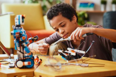 Zeki Afrikalı çocuk evde fen dersi için robot yapıyor. Robot Bilimi ve Eğitim.