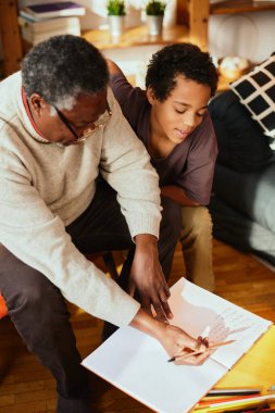Afrikalı bir dede torununa matematik problemini nasıl çözeceğini gösteriyor. Aile desteği